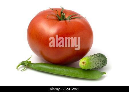 Eine große Tomate, eine kleine Gurke und eine Schote junger grüner Erbsen. Frisches Gemüse isoliert auf weißem Hintergrund Stockfoto