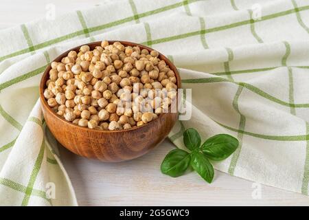 Rohe, trockene Kichererbsen in einer braunen Holzschüssel auf einem weiß grünen Küchentuch. Hummus und gesunde vegetarische Lebensmittel rohe Zutat. Pflanzliches Eiweiß. Stockfoto