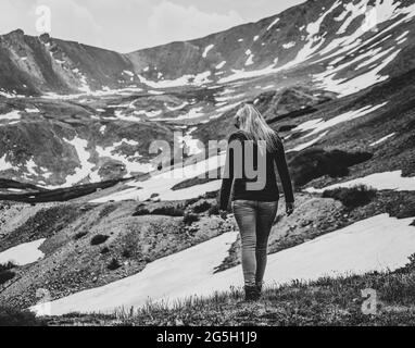 Schwarz-weißes Bild einer schönen Frau, die auf dem hohen Berggipfel wandert Stockfoto