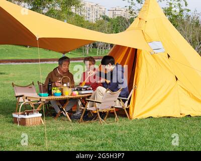 Eine glückliche Familie von drei, die ein Picknick im Freien mit hochwertigen Fotos macht Stockfoto