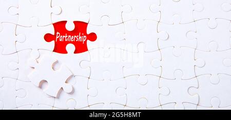 Puzzle auf rotem Hintergrund mit Partnerschaftswort. Geschäftskonzept. Stockfoto