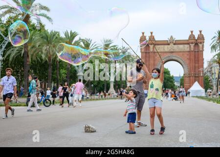 Barcelona, Spanien. Juni 2021. Touristen spielen mit Blasen in der Nähe des Arc de Triomf in Barcelona, Spanien, 26. Juni 2021. UM MIT "Spaniens größten Städten zu GEHEN, starten Kampagnen, um int'l Besucher zurück zu locken" Credit: Zhang Cheng/Xinhua/Alamy Live News Stockfoto