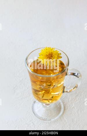 Gesunder Kräutertee mit Delelionen in einer Glasschale, Eis und gelber Dandelionenblume innen auf weißem Hintergrund, Draufsicht, Kopierraum, vertikales Format Stockfoto