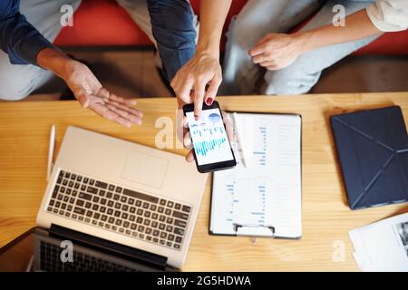 Hände von Geschäftsleuten diskutieren Diagramme und Diagramme auf dem Bildschirm des Smartphones, Blick von oben Stockfoto