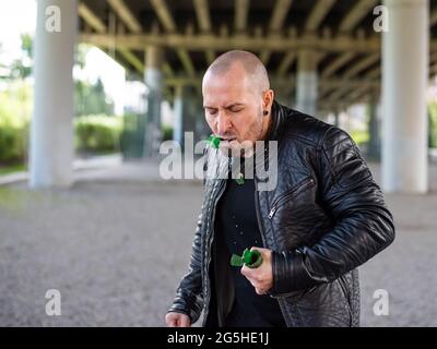 Kahlköpfiger kaukasischer Mann, der zerbrochenes Glas isst Der Bandit isst eine Flasche Zucker. Witz oder Magie Stockfoto