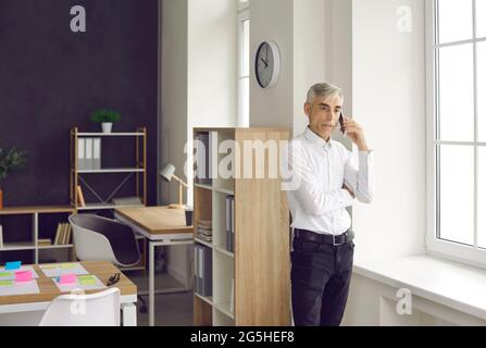 Der leitende Geschäftsmann ist damit beschäftigt, mit einem Mobiltelefon zu sprechen, um verschiedene Probleme bei der Arbeit zu lösen. Stockfoto