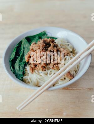 Selektiver Fokus einer Schüssel indonesischer Hühnernudeln oder Mie ayam serviert mit grünem Senf Stockfoto