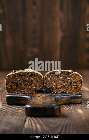 Hausgemachtes Roggenbrot mit getrockneten Aprikosen, Pflaumen und Sonnenblumenkernen, die auf die Hälfte geschnitten sind Stockfoto