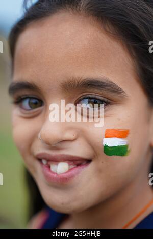 Nahaufnahme der dreifarbigen indischen Flagge gemalt auf glücklich lächelnden jungen Mädchen Kind Gesicht während der indischen Unabhängigkeit oder republik Tag Feier - Konzept der