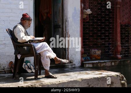 Varanasi, Banaras, Uttar Pradesh, Indien - 02. Februar 2021, Indian Old man Reinigung des Reises auf traditionelle Weise oder manuell finden Kommissionierung der Steine A Stockfoto