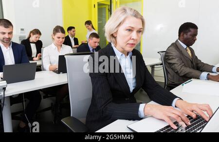 Reife Frau, die im Großraumbüro arbeitet Stockfoto