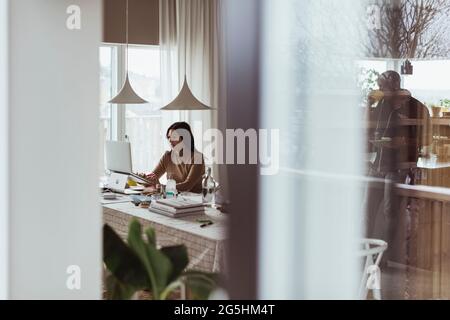 Weibliche Profikanin, die im Heimbüro am Laptop arbeitet Stockfoto