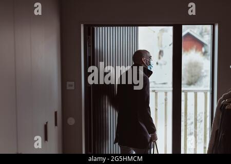 Geschäftsmann mit Schutzmaske beim Gang durch die Tür während des COVID-19 Stockfoto