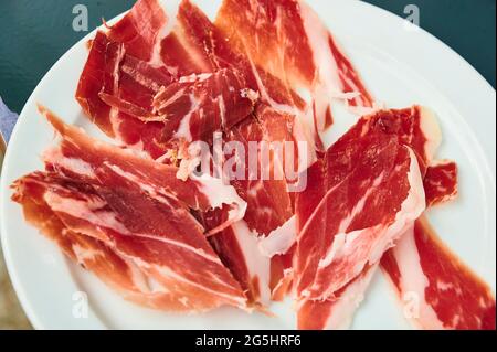 Blick auf den Teller mit geschnittenem Iberico-Schinken, der in der Gastronomie zum Essen bereit ist Stockfoto