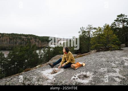 Weibliche Wanderin, die während des Urlaubs an Zweigen auf dem Berg sitzt Stockfoto