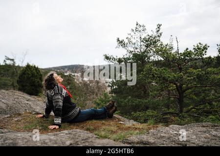 Seitenansicht einer Wanderin, die auf einem Felsen im Wald sitzt Stockfoto