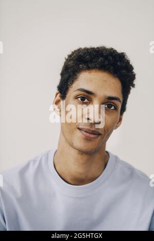 Lächelnder junger Mann vor weißem Hintergrund Stockfoto