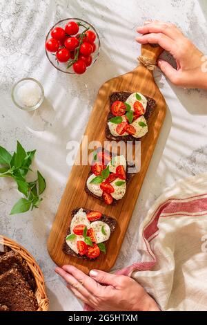 Vollkornbrot-Sandwiches mit Käse, Tomaten und Basilikumblättern, Draufsicht. Gesundes Snack-Konzept. Stockfoto