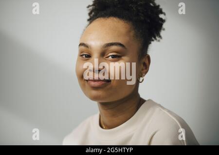 Porträt einer lächelnden jungen Frau an der weißen Wand Stockfoto