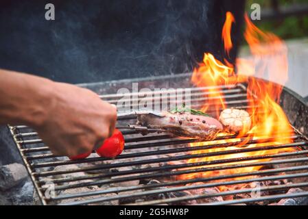 Grill heißes gegrilltes Fleisch mit Feuerflamme Hitze bbq Kochen Abendessen Brennen von Holzkohle. Braten Steak Grillen mit Feuer und Rauchen Kochen draußen. Rindfleisch Stockfoto