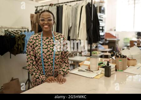 Lächelnde afrikanische Modedesignerin, die in ihrem Studio arbeitet Stockfoto