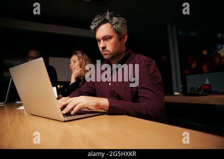 Porträt eines ernsthaften männlichen Geschäftsmannes, der im Büro am Laptop am Schreibtisch arbeitet Stockfoto