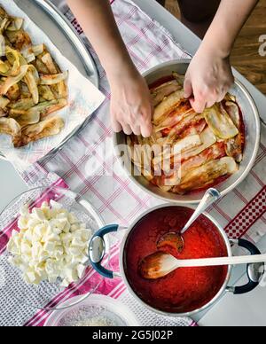 Vorbereitung von Auberginen Parmesan. Foto von oben mit den Zutaten und den Händen des Kochs. Stockfoto