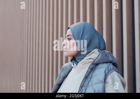 Grafische Seitenansicht Porträt einer modernen Frau aus dem Nahen Osten, die im Freien Kopftuch trägt, Fokus auf starkes Profil, Kopierraum Stockfoto
