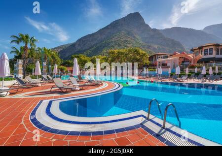 Schöner Swimmingpool mit Sonnenliegen und Sonnenschirmen bei Sonnenaufgang Stockfoto