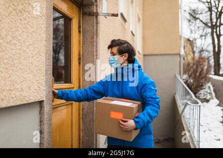 Wichtige Servicefrau, die während der COVID-19 das Paket auslieferte Stockfoto