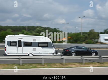 Linthe, Deutschland. Juni 2021. Ein Auto mit Wohnwagen befindet sich auf der Autobahn A9. Ferien im eigenen Land und mit eigenem oder geliehenem Wohnmotorheim sind derzeit sehr trendy. Vielen neuen Camper fehlt jedoch die Erfahrung, mit den großen Fahrzeugen und Anhängern sicher in den Urlaub zu starten, so die Polizei. Dies beginnt mit der richtigen Beladung und endet mit dem Einsatz von Sicherheitsgurten in den umfahrenden Wohnräumen. Quelle: Patrick Pleul/dpa-Zentralbild/ZB/dpa/Alamy Live News Stockfoto