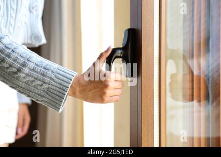 Nahaufnahme einer Frau, die zu Hause eine Fenstertür öffnet Stockfoto