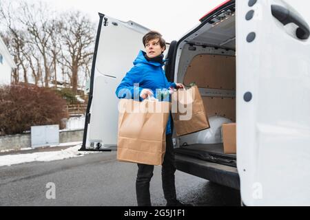 Weibliche Person, die Papiertüten aus dem Lieferwagen auslädt Stockfoto