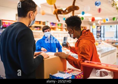 Männlicher Lieferer, der dem Unternehmer an der Kasse im Geschäft ein Smartphone zeigt Stockfoto