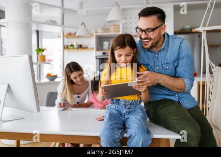 Eltern helfen Kindern, die online zu Hause studieren. Lockdown und Online-Schule, Technologie-Konzept. Stockfoto