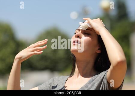 Gestresste asiatische Frau trocknet Schweiß mit einem Tuch an einem warmen Sommertag Stockfoto