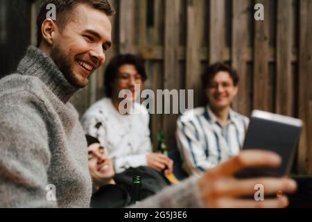 Glückliche männliche Freunde, die Selfie über das Mobiltelefon auf dem Balkon machen Stockfoto
