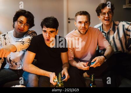 Junge männliche Freunde spielen Videospiel zu Hause Stockfoto