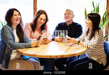 Freunde, die mit Mobiltelefonen in einer Bar Spaß haben - Smartphones in den Händen von Millennials lachen und Freude - Technologie und soziale Netzwerke kommunizieren Stockfoto