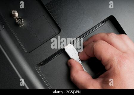 Man stecke ein weißes usb-Kabel an einen Smart TV Stockfoto