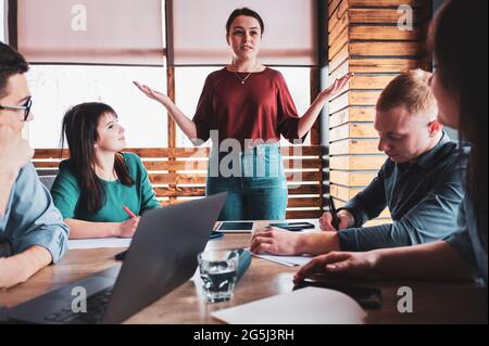 Die Chefin hält ein Treffen im Büro mit Kollegen ab - Geschäftsfrau lehrt andere Mitarbeiter, im Büro Erfolg zu erzielen - die Trainerin spricht Stockfoto