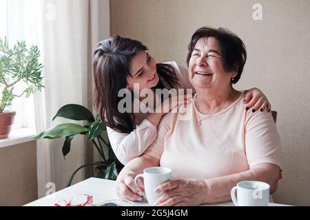 Umarmungen von einer älteren Großmutter und einer jungen Tochter - gute Beziehungen zwischen den Generationen - Großmutter und Enkelin haben Spaß zusammen im Stockfoto