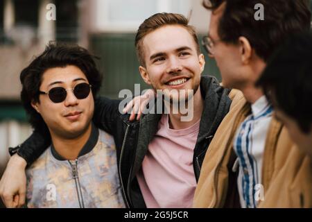 Lächelnde junge männliche Freunde, die miteinander reden Stockfoto