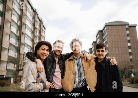 Porträt lächelnder männlicher Freunde mit den Armen in der Stadt Stockfoto