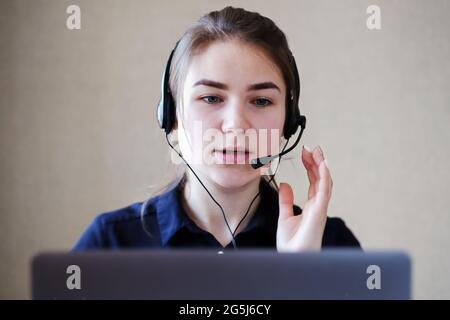 Junge Callcenter-Mitarbeiterin, die mit einem Kunden in einem Headset spricht - Telemarketing-Mitarbeiter in einem Büro mit Laptop gibt Kunden Ratschläge - Co Stockfoto
