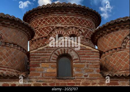 Hinter dem westlichen Ziegelgiebel der Cattolica di Stilo, einer byzantinischen Klosterkirche oberhalb von Stilo in Kalabrien, erhebt sich ein zentraler Trommelturm, der mit Terrakottafliesen in diagonalen Mustern verziert und von einer flachen Pantiled-Kuppel bedeckt ist. Der zentrale Turm der Kirche wird in diesem Bild von zwei der anderen vier Türme flankiert, die aus dem Dach der Kirche ragen. La Cattolica wurde in den 800er Jahren n. Chr. von troglodyten basilianischen Mönchen nach einem quadratischen griechischen Kreuzplan erbaut. Es hat vier wiederverwendete Mittelsäulen aus der antiken griechischen Küstenkolonie Kaulonia oder Kaulon, die 200 v. Chr. von Rom zerstört wurde. Stockfoto