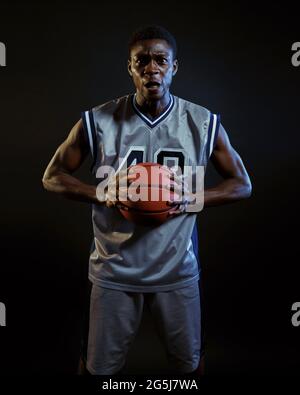 Aggressiver Basketballspieler posiert mit Ball Stockfoto