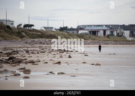 Menschenleerer Sandstrand im Winter Plurien Frankreich Bretagne mit einsamen älteren Spaziergängen Stockfoto