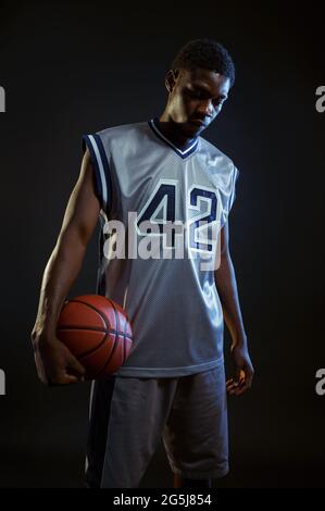 Aggressiver Basketballspieler posiert mit Ball Stockfoto