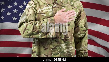 Zusammensetzung des Mittelteils des Soldaten mit Hand auf Herz, gegen amerikanische Flagge Stockfoto